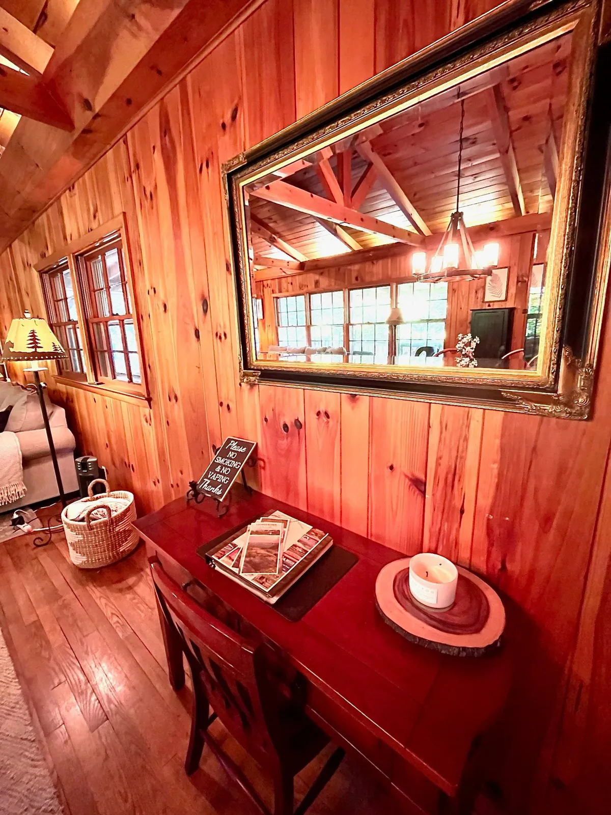 This image showcases a cozy workspace featuring wooden walls, a desk, a lamp, and a mirror—evoking a productive yet inviting atmosphere. The desk is neatly arranged, suggesting readiness for remote work or quiet reading.