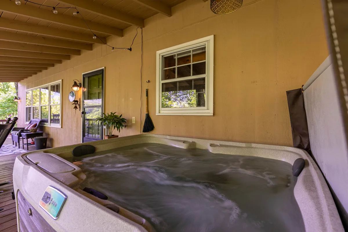 This interior shot highlights a luxurious hot tub surrounded by a comfortable seating area and large windows that reveal the scenic views outside. Decorative light fixtures add warmth and ambiance to the space, making it an ideal spot for relaxing after an active day.