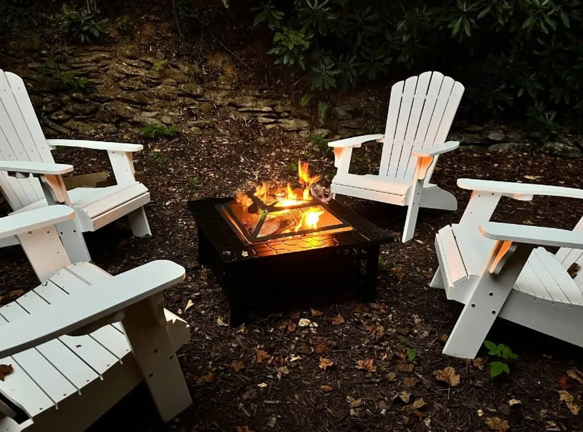 An inviting fire pit is surrounded by Adirondack chairs and lush foliage, creating a warm and social ambiance for evening gatherings, storytelling, or stargazing under the open sky.